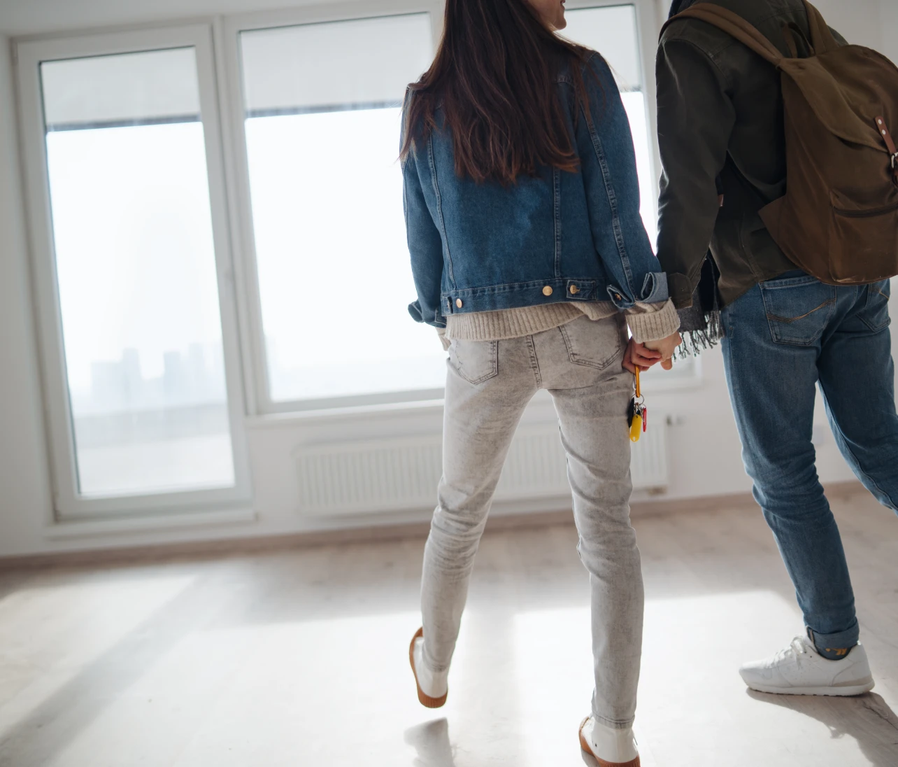 Photo of couple holding hands looking at new apartment
